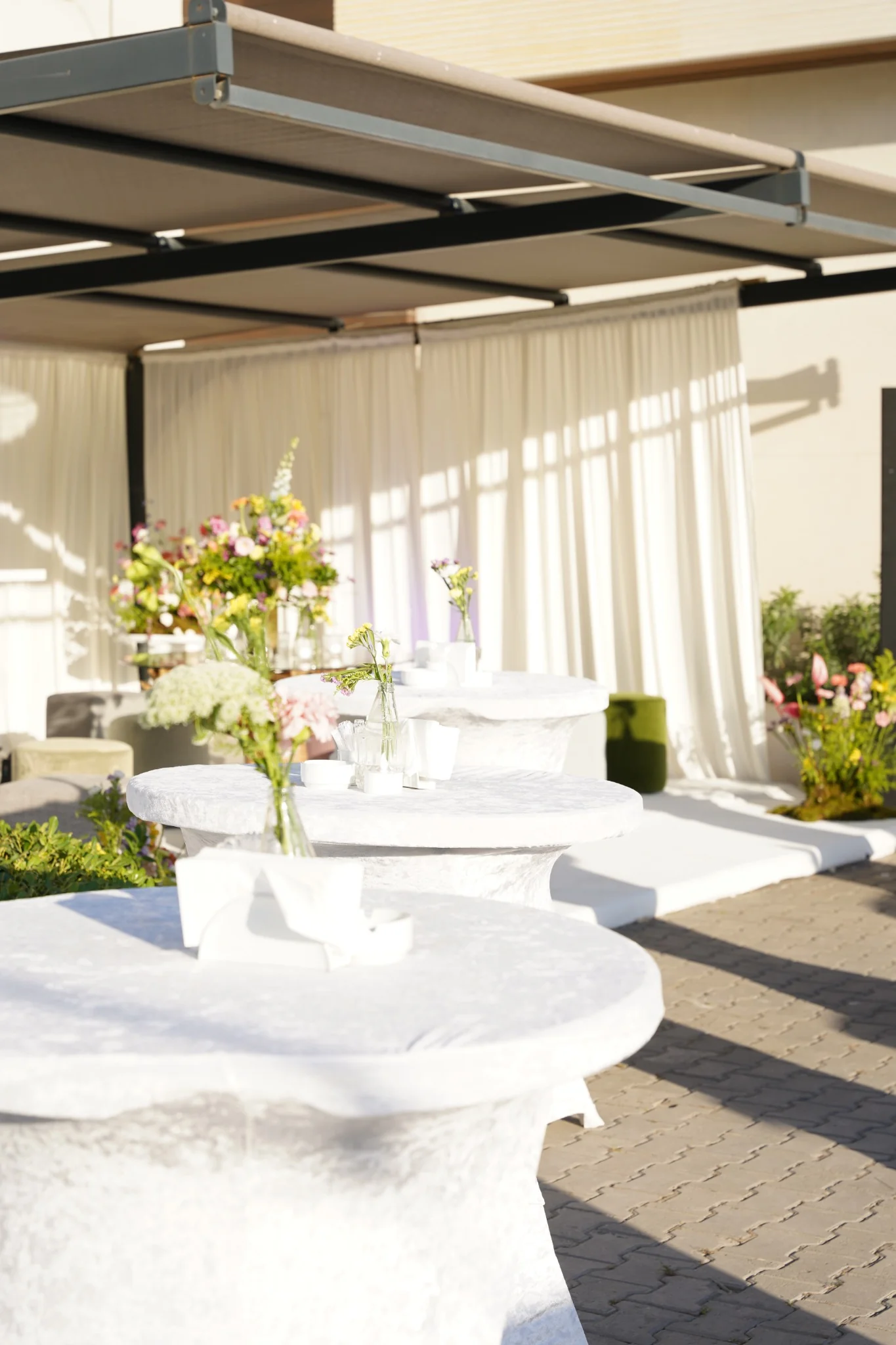 Showroom lansmanı için hazırlanan beyaz bistro masalar ve çiçek düzenlemeleri